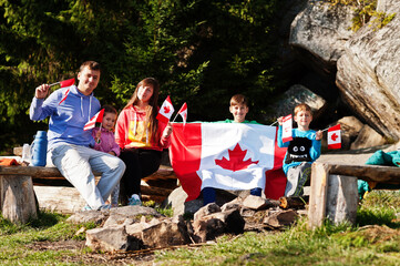 Happy Canada Day. Family with large Canadian flag celebration in mountains.