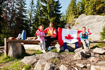 Happy Canada Day. Family of mother with three kids hold large Canadian flag celebration in...