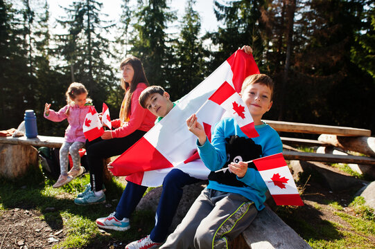 Happy Canada Day. Family of mother with three kids hold large Canadian flag celebration in mountains.