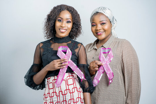 selective focus of beautiful african women, holding symbols attached to the chest- breast cancer awareness concept