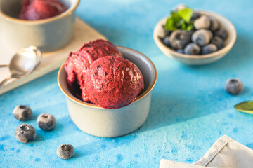 Homemade vegan banana ice cream or gelato with blueberry in a bowl  on blue  background. Healthy dessert.
