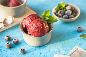 Homemade vegan banana ice cream or gelato with blueberry in a bowl  on blue  background. Healthy dessert.