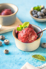 Homemade vegan banana ice cream or gelato with blueberry in a bowl  on blue  background. Healthy dessert.
