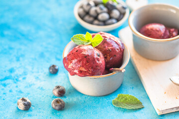 Homemade vegan banana ice cream or gelato with blueberry in a bowl  on blue  background. Healthy dessert.