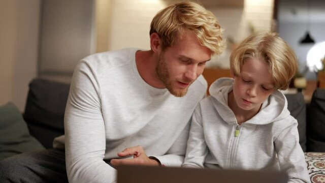 Close-up view of the father is doing homework with his son at the computer