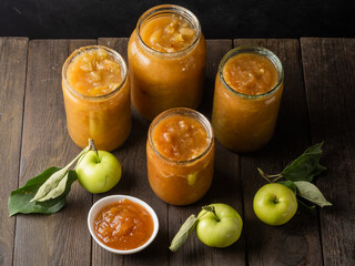 Tasty homemade apple jam, confiture in a glass jar with apples on a black wooden table