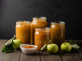 Tasty homemade apple jam, confiture in a glass jar with apples on a black wooden table