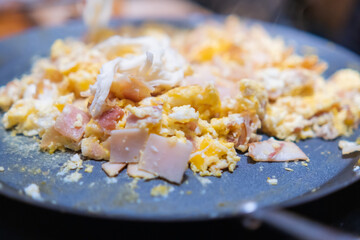 Scrambled eggs with chopped turkey ham on a round griddle