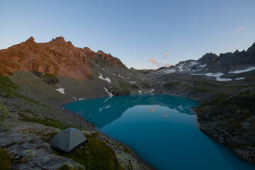 Naklejka premium A wonderful view to the horizon at a beautiful sunset in the alps of Switzerland by an alpine lake called Schottensee. These colors by the sunset are just amazing. Epic clear blue water.