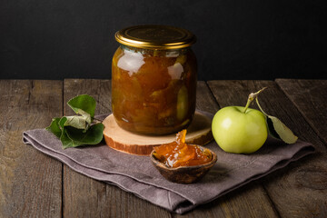 Tasty homemade apple jam, confiture in a glass jar with apples on a black wooden table