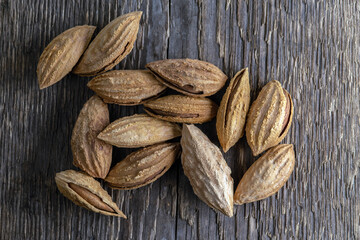 Inshell almonds on a background of rough wood texture. Selective focus.