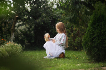 маленькая девочка с любимой куклой в саду парке 
little girl with her favorite doll in the garden park