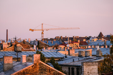 Tower crane on construction site on blue sky background and cityscape. City skyline in morning sunlight. Selective focus