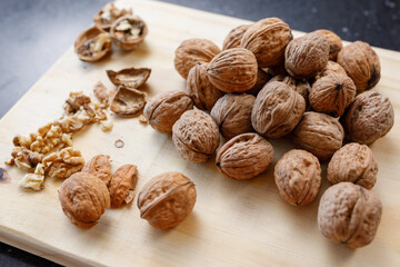 Whole and cracked walnuts on a wooden board.