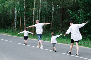 cheerful family of four people having fun, spreading hands as wings imitating plane, pretending flying, going on journey