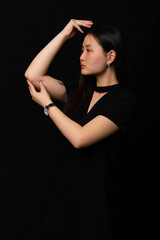 portrait of a girl in black clothes with long black hair on a black background. Oriental beauty