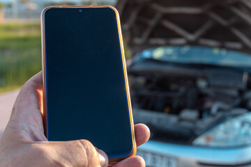 Close-up with selective focus of a phone ready to call the roadside assistance service, with a...