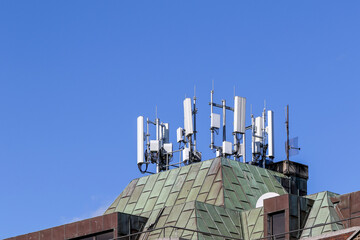 Mobile or cell phone radio antennae on roof of building. White equipment against blue sky. Dublin, Ireland