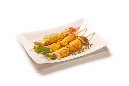 pinchos morunos de cerdo pollo adobado fresco crudo sobre plato blanco con servilleta de tela gris, aislado fondo blanco