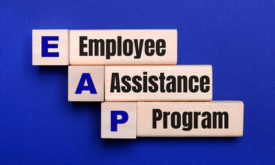 On a bright blue background, light wooden blocks and cubes with the text EAP Employee Assistance...