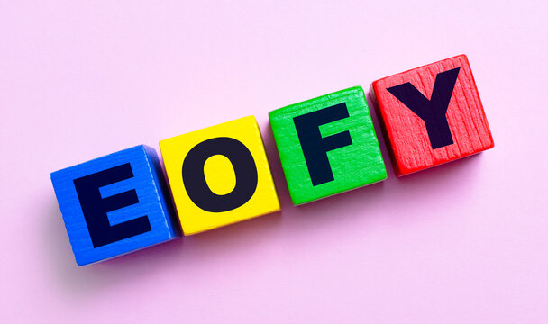 On a light pink background, multi-colored wooden cubes with the text EOFY.