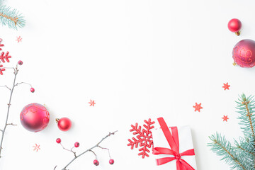 Flat lay christmas frame with red berries, fir branches, snowflakes, red balls and gift box on a white background. Merry christmas card and copy space for your text