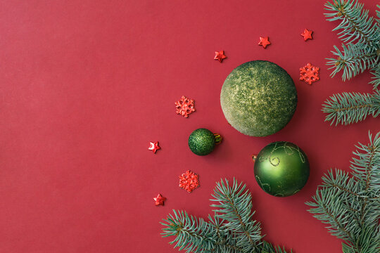 Flat lay frame with fir branches and christmas balls on a red background