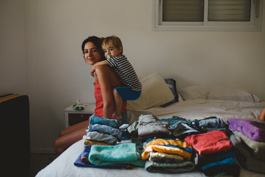Mother and son having fun near a pile of folded clothes