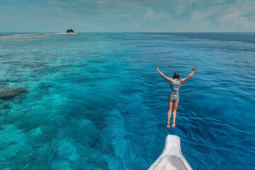 Young woman jumping from a boat