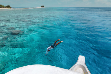 Young man jumping from a boat
