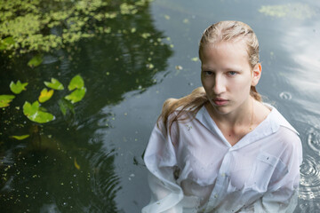 Blonde teenage girl  in white shirt with wet hair is in the the bog
