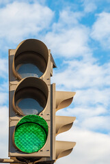 Traffic light on the background of the sky with clouds. The green color of the signal.