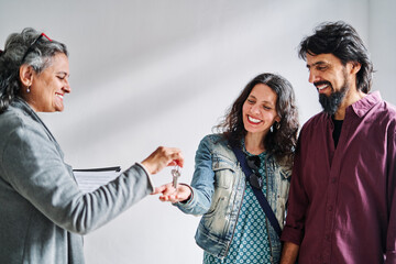 Real estate agent handing over keys to the apartment to clients