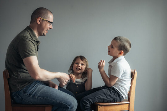 Portrait of father and children talking on the grey background.
