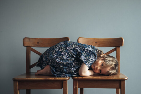 Little cute girl lying on the chairs.