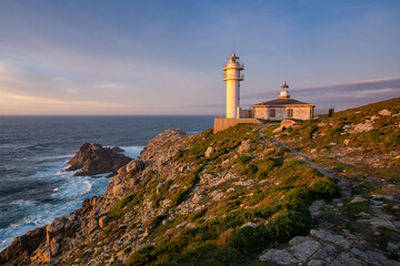 Fototapeta na wymiar Sea landscape view of Cape Tourinan Lighthouse at sunset with pink clouds, in Spain