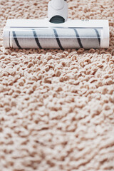 The turbo brush of a cordless vacuum cleaner cleans the carpet in the house in close-up