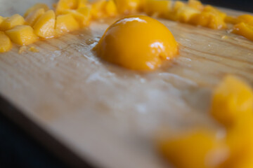 Small pile of chopped peaches around half a peach on wooden surface