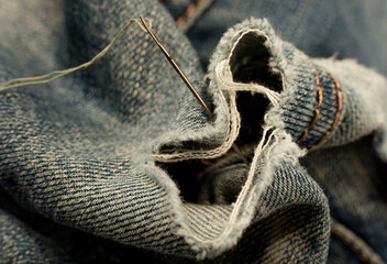 Hole in jeans. Needle with thread for darning jeans. Tools for work dressmaker, seamstress fashion...