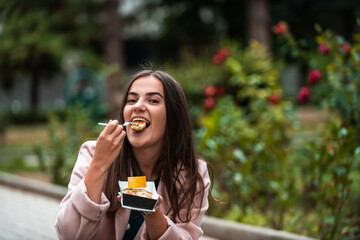 A beautiful smiling girl eats fresh poffertjes while touring the city. Selective focus.