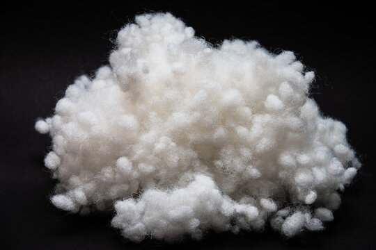 Synthetic fiber, siliconized holofiber, polyester fiber, white synthetic winterizer on a black background. It is used as a filler for blankets, pillows, clothes and upholstered furniture. Close-up.