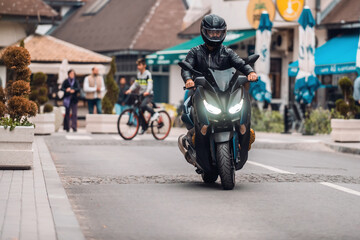 Modern motorcyclist drives on a motorcycle on the road in city. Selective focus