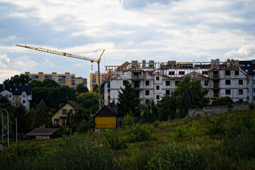 Budowa  dużego domu mieszkalnego , widoczne rusztowania i dźwig ( żuraw)   na tle błękitnego nieba z białymi chmurkami .Construction of residentia on a background of a blue sky with white clouds.  © Grzegorz