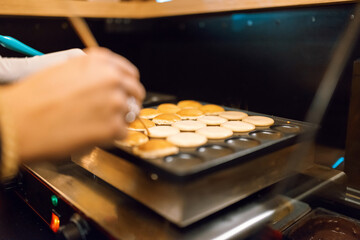 The process of making fresh delicious poffertjes. Making fresh poffertjes.Traditional Dutch batter treat. Selective focus