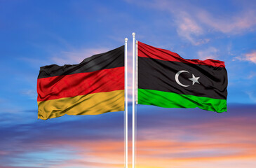 Libya and Germany flag waving in the wind against white cloudy blue sky together. Diplomacy...