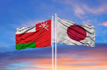 Oman and Japan two flags on flagpoles and blue sky