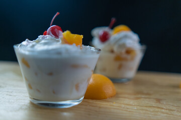 Cup of peaches and cream on wooden board with black background