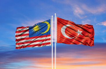 Turkey and Malaysia flag waving in the wind against white cloudy blue sky together. Diplomacy concept, international relations.