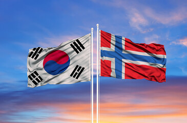 flags of South Korea and Norway waving in the wind on flagpoles against sky with clouds on sunny day. Symbolizing relationship,