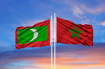 Maldives and Morocco flag waving in the wind against white cloudy blue sky together. Diplomacy concept, international relations.